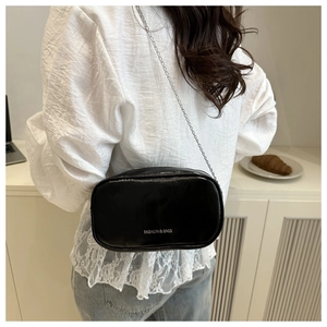 Detail of a mini glossy black crossbody bag with silver lettering and metal chain