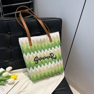 Green and white woven summer tote bag with embroidered letters and brown leather handles