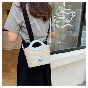 Detail of summer straw bucket bag with white lace trim and blue leather strap