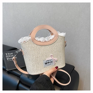 Close-up of straw woven handbag with white lace trim, pink bow, and leather strap
