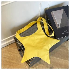 Détail d'un sac à bandoulière en toile jaune vif en forme d'étoile sur une valise