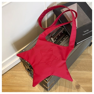 Détail du sac bandoulière en toile rouge en forme d'étoile sur une valise argent