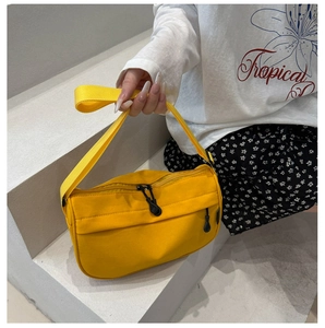 Close-up of a vibrant yellow crossbody bag with double zippers and a wide nylon strap