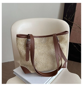 Detail of straw tote bag showing woven texture, brown leather trim and adjustable straps