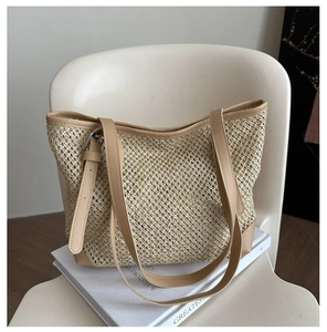 Detail of straw woven tote bag featuring light brown leather handles on a white chair