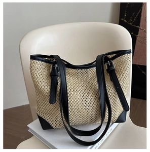 Close-up of woven straw tote bag with black leather reinforced corners and silver buckle