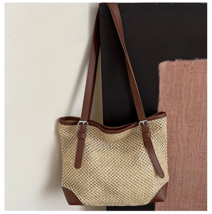 Detail of woven summer tote bag showing adjustable brown leather straps and silver buckle