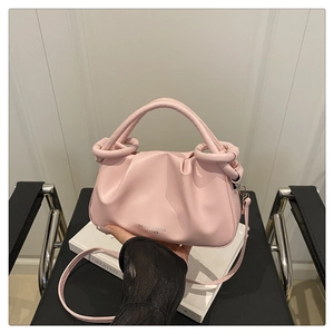 Detail of pink pleated cloud bag featuring metal ring handle and leather texture