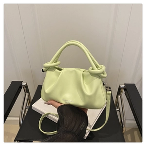 Detail of avocado green pleated leather handbag featuring a knotted handle and logo