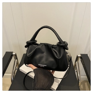 Detailed shot of a black pleated cloud bag with leather texture and top handle