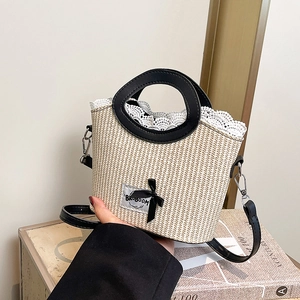 Chic beige woven bucket bag with lace trim, black bow detail, and leather handles