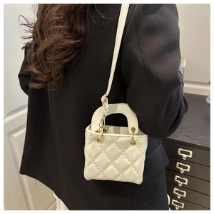 Détail du sac matelassé blanc avec ferrures dorées sur une veste de costume noire