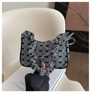 Detail der karierten Hobo-Tasche mit schwarzen Schleifen und gerafftem Griffdesign