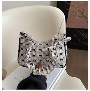 Detail der karierten Handtasche mit schwarzen Schleifen und gerafftem Scrunchie-Griff