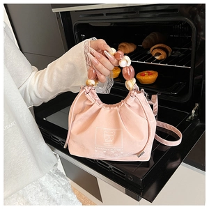 Pink satin drawstring bag detail featuring large colorful bead handle and bear pattern
