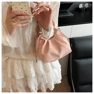 Detailed texture of pink pleated fabric bag featuring resin ring handle and chic print