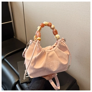 Close-up of pink drawstring bucket bag with decorative orange beaded handle and bear patch