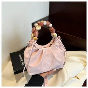 Detail of pink bucket bag with amber beaded handle and drawstring closure on silk