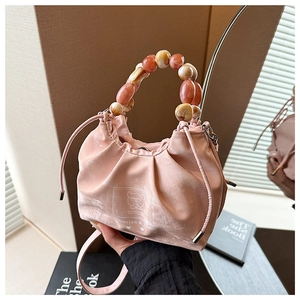 Detailed shot of pink pleated crossbody bag with decorative marble beaded handle