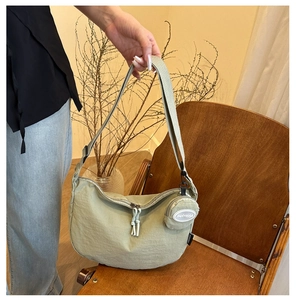 Detail of light green crescent bag with wide strap and round coin purse pouch