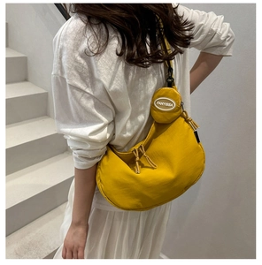 Macro shot of bright yellow nylon crescent bag with mini coin purse and tassel zipper detail