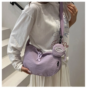 Close-up of light purple crescent bag with adjustable strap and small round coin purse