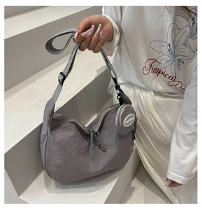 Close-up of a grey nylon crescent crossbody bag with adjustable strap and small coin purse
