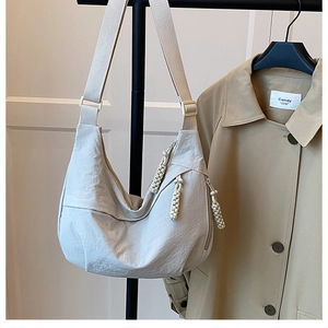 Detail view of the beige dumpling crossbody bag featuring a woven rope zipper puller