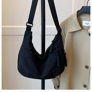 Detail of black nylon hobo bag showing adjustable strap and textured zipper pendant