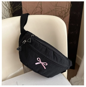 Close-up of black nylon waist bag featuring a pink bow embroidery and adjustable strap