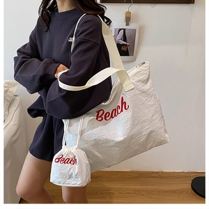 Lifestyle-Foto eines weißen Nylon-Shoppers mit rotem Beach-Aufdruck und kleiner Tasche