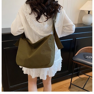 Detail of army green nylon crossbody bag showing the flap design and wide shoulder strap