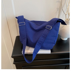 Close-up of royal blue nylon crossbody bag with wide shoulder strap and metal hardware