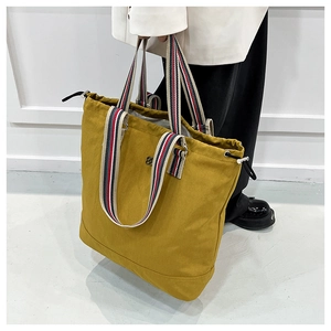 Detail of ginger tote bag with striped webbing handles and side drawstring adjustment