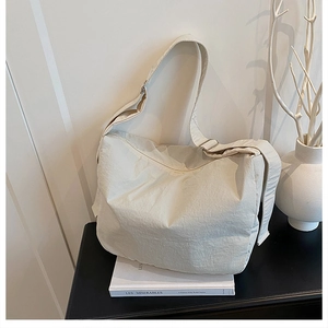 Detail of off-white nylon dumpling bag featuring durable fabric and adjustable strap