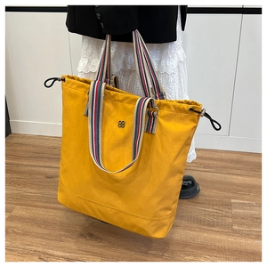 Detail of ginger yellow large tote bag with colorful striped handles and clover logo