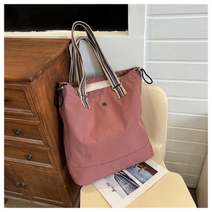 Detailed macro view of the vintage pink canvas tote bag with striped straps and logo