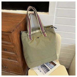 Detail of army green canvas tote with colorful striped straps and drawstring closure