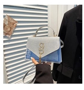 Detail of blue quilted PVC bag with silver glitter flap and gold logo with fringe