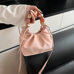 Pink drawstring bucket bag with marble beaded handle and crossbody strap