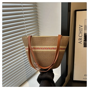 Detail der geflochtenen Strohtasche mit braunen Ledergriffen und bunten geometrischen Mustern