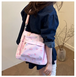 Detail of pink floral crossbody bag with rose patterns and multiple zipper pockets