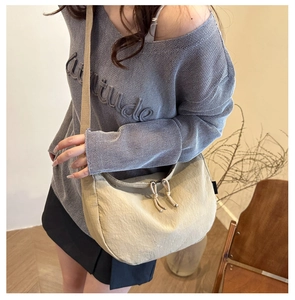 Detail of beige crescent crossbody bag featuring durable nylon fabric and adjustable strap
