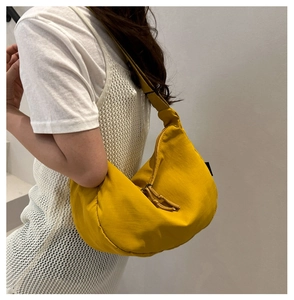 Detail of minimalist yellow nylon crescent bag showing its texture and matching zipper strap