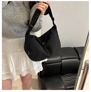 Detail of black crescent shoulder bag with adjustable strap and side fabric label