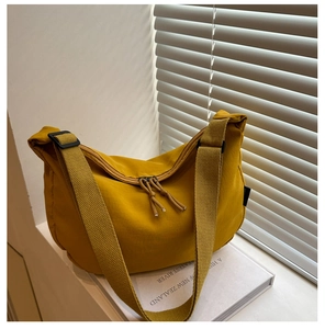 Detail of a ginger yellow nylon crescent bag featuring adjustable strap and double zippers