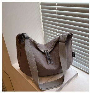 Detail of grey-brown nylon tote bag with texture, wide strap, and knot zipper pull