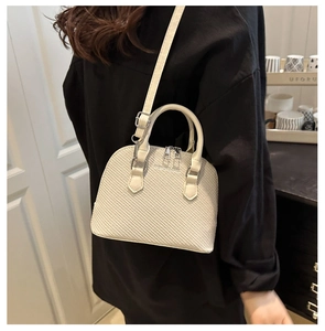 Detail of cream shell bag with woven texture, silver hardware and adjustable strap