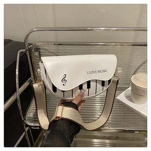 Détail d'un sac selle blanc avec motif touches de piano et bandoulière large ajustable