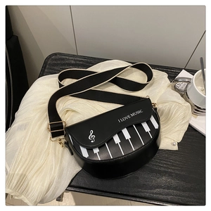Détail du sac selle avec motif de touches de piano et bandoulière large bicolore